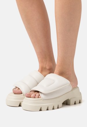 Weiße Riemchensandalen mit gepolstertem Riemen, offener Zehenpartie und dicker, strukturierter Sohle. Verfügt über ein klobiges, geripptes Plattformdesign.
