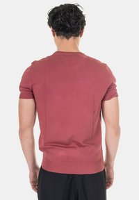 Maglione a maniche corte in un morbido colore terracotta. Texture a coste sui polsini e sull'orlo, vestibilità classica, scollo rotondo e design della schiena senza cuciture.