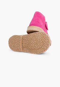 Boots de gleznă din suede roz cu o talpă din cauciuc brun texturată și o curea ajustabilă cu arici pe lateral.