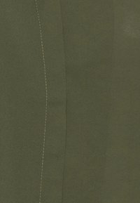 Olive green fabric with a smooth texture, featuring a prominent seam highlighted by contrasting yellow stitching, showcasing an elongated shape.