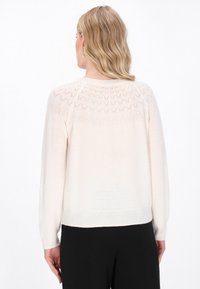 Crème-kleurige gebreide trui met een getextureerde rugpand met geometrische patronen, lange mouwen en geribbelde manchetten en onderrand.