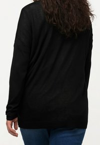 Schwarzer, lässig geschnittener Pullover mit langen Ärmeln, runder Ausschnittform und gerippten Bündchen und Saumdetails. Weicher, strukturierter Stoff.