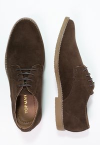 Chaussures en daim marron à lacets avec un bout arrondi, des coutures contrastantes et une semelle en caoutchouc. Présente un design simple et des accents minimalistes.