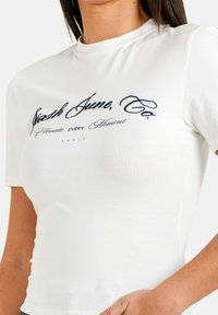 Hvid kortærmet t-shirt lavet af bomuld, med et marineblåt skrivet logo og tagline trykt i midten. Slim-fit design.