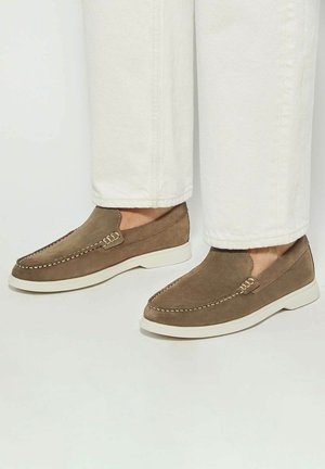 Brown suede slip-on shoes with white rubber soles and decorative stitching along the edges, featuring a smooth texture and simple design.