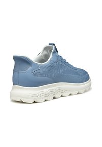 Sneaker bleu clair avec un dessus en maille texturée et des accents en cuir lisse. La semelle est blanche avec un design en vagues, offrant un bon amorti.