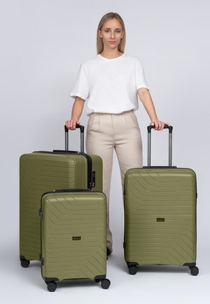 Trois valises rigides vert olive avec un design strié, accompagnées de poignées télescopiques et de roues lisses, empilées en rang.