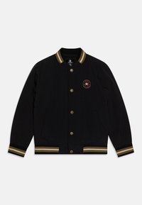 Zwarte bomberjack met een gebreide kraag, voorzien van goud- en zwarte strepen. Heeft knoopsluitingen en een rood geborduurd sterlogo op de borst.