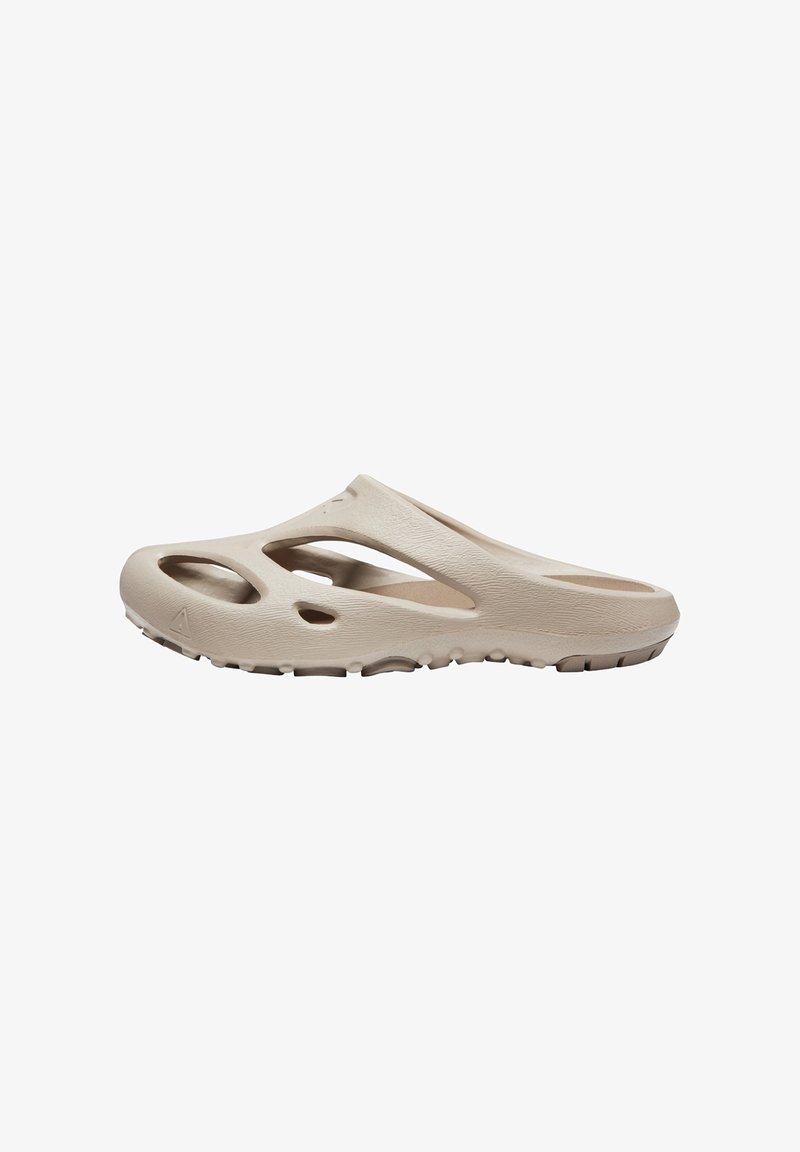 Chaussure beige à enfiler avec plusieurs grands trous de ventilation et semelle texturée pour le confort et l’adhérence.