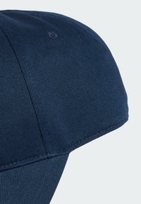 Navy blue cap with a rounded crown, structured visor, textured fabric, and stitched accents. Features a small ventilation hole on top.