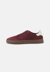 Burgundy suede sneakers with tonal stitching, a contrasting white heel cap, and a brown rubber sole. Simple, low-profile design.