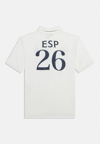 Λευκό polo με κοντά μανίκια και γιακά, με την ένδειξη "ESP" και τον αριθμό "26" τυπωμένα σε μεγάλο σκούρο γράμμα στην πλάτη.
