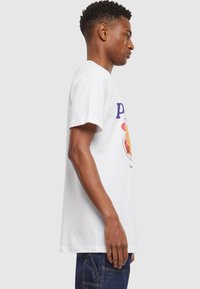 White cotton t-shirt featuring a colorful graphic print of a plate with pancakes and syrup. Short sleeves and a relaxed fit design.