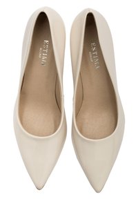 Bēšas lakotas ādas augstpapēžu kurpes ar smailu purngalu, kas iezīmējas ar gludu tekstūru un smalku iekšējo oderes rakstu. Redzams zīmola logo iekšpusē.