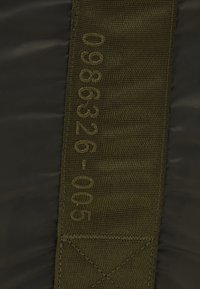 Panneau de tissu rectangulaire en vert olive foncé avec des accents cousus, des chiffres en relief et un matériau tissé texturé pour une durabilité accrue.