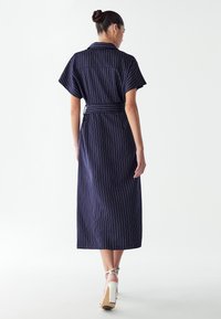 Merineel riba kiilukleid, millel on lühikesed varrukad, krae disain ja vöökoht, valmistatud kergest kangast.