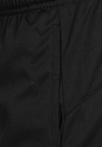 Sorte athletic shorts med elastisk talje, der har en sidelomme og tekstureret stof for holdbarhed. Flade syninger er synlige.