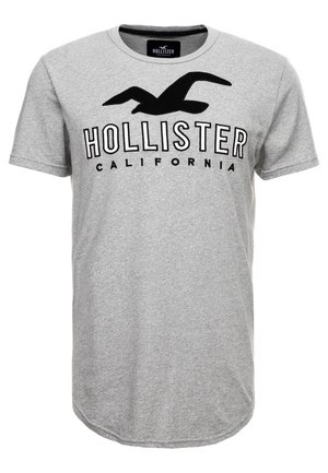 Jasnoszara koszulka z krótkim rękawem z czarnym logo mewy nad napisem "HOLLISTER CALIFORNIA" na środku przodu.