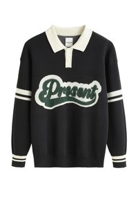 Pull en tricot noir avec un col blanc, arborant un logo "Cadeau" en fausse fourrure verte et des accents rayés blancs sur les manches.