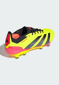 Scarpe da calcio gialle brillanti con strisce nere, dettagli rosa e diversi tacchetti. Presentano un collare imbottito e un sistema di allacciatura per una vestibilità ottimale.