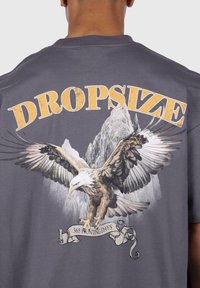 Gray cotton t-shirt featuring a large eagle graphic, mountains in the background, and the text "DROPSIZE" and "365 HUNTING DAYS" in bold, distressed yellow.