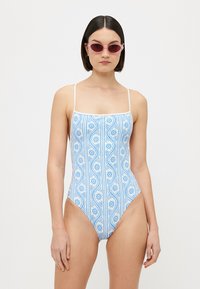 Maillot de bain une pièce avec un motif floral et à rayures bleues, des bretelles blanches et un décolleté carré. Le tissu semble lisse et ajusté.