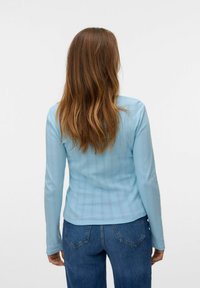 Lichtblauwe lange mouwen top van een gestructureerde stof met verticale strepen en kleine diamantpatronen, gecombineerd met blauwe broek.