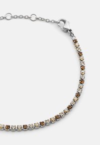 Ezüst színű karkötő, váltakozó barna és átlátszó kubikus zirkón kövekkel, prong beállítással, csattal ellátott záródással.
