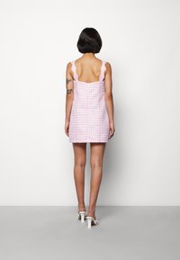 Robe en vichy rose avec bretelles festonnées, corsage ajusté et jupe évasée, en tissu texturé. Dos nu, longueur au-dessus du genou.