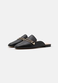 Svarta läder loafers med spetsig tå, låg klack och metallisk guldkedja över framsidan. Slät yta och minimalistisk design.
