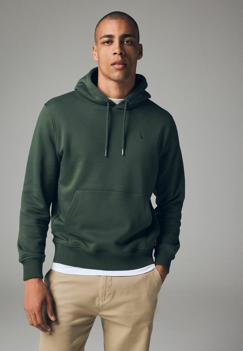 Sudadera verde oscura hecha de tela suave, con bolsillo canguro, dobladillo acanalado, capucha con cordón y un pequeño logo en el pecho.