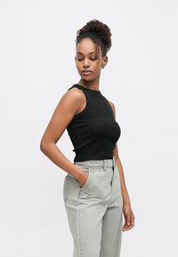 Čierny tielkový top so žebrovanou textúrou, kombinovaný so svetlosivými vysokými nohavicami s prednými vreckami, ktoré majú voľný strih.