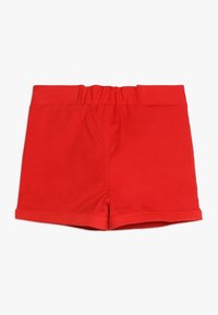 Czerwone szorty z elastycznym pasem, gładką fakturą i podwiniętym dołem. Prosty design, bez dodatkowych wzorów czy detali.