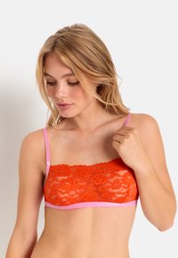 Kant bralette in feloranje met roze satijnen bandjes. Bevat bloemmotieven en een gestructureerd oppervlak, ontworpen voor comfort en ondersteuning.