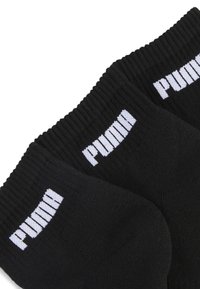 Czarne bawełniane skarpetki z prążkowanymi mankietami, z białym logo "PUMA" na górze. Standardowa długość do kostki o gładkiej fakturze.