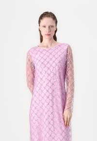 Lange mouw, lichtroze jurk met een doorschijnende overlay met een ruitpatroon en versieringen, gladde textuur met een ronde halslijn.