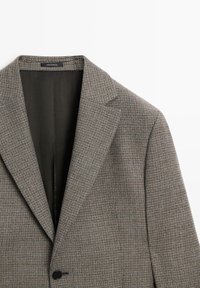 Checkered blazer in textured fabric, brown and gray tones, featuring a notched collar, single button closure, and a smooth interior lining.