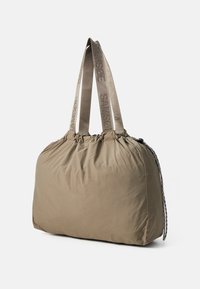 Kaki tote bag med en myk, quiltet tekstur. Har robuste, teksturerte stropper med präget merkevare og en snøring detalj.