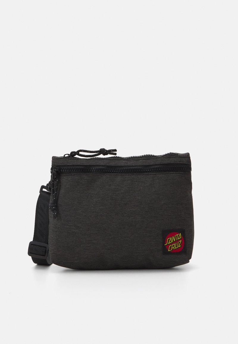 Black fabric pouch with a textured surface, featuring a zipper closure and an adjustable strap. Includes a colorful Santa Cruz logo patch.