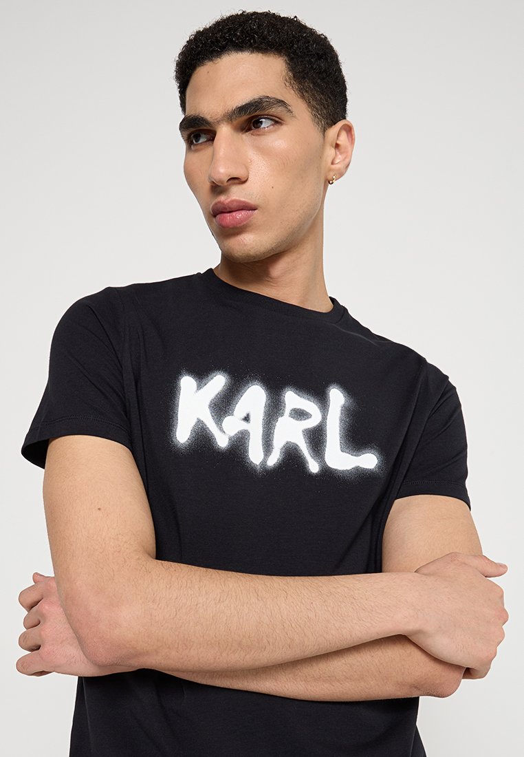 T-shirt en coton noir avec un texte graphique audacieux en blanc "KARL" dans un style de spray. Manches courtes et col rond.