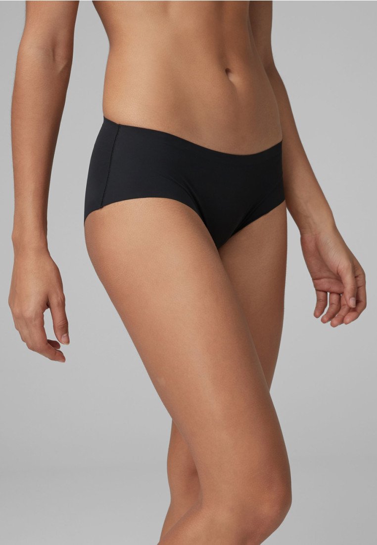 Černé bikiny s hladkým, matným povrchem. Mají nízký střih a minimální krytí. Tkanina vypadá elasticky a leskle.