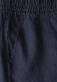 Marinblått linne tyg med en strukturerad yta, elastisk midja och sidoseamsdetaljer. Lämplig för avslappnad klädsel.