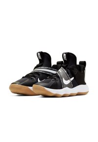Nike sneakers neri presentano una tomaia testurizzata, fasce elastiche con il testo "Just Do It" e una suola intermedia bianca abbinata a una suola in gomma color cuoio.