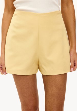 Shorts jaunes ajustés avec une texture lisse, taille haute et lignes épurées, sans poches visibles ni embellissements.