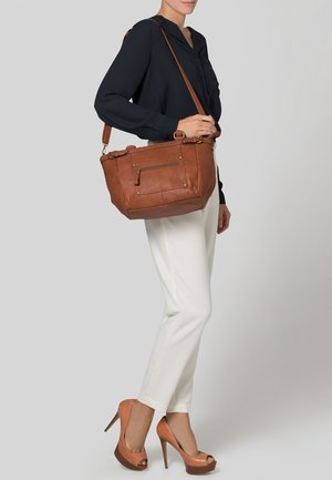 Sac à main en cuir marron avec une poche zippée, une bandoulière réglable, une forme structurée et des accents de quincaillerie dorée.