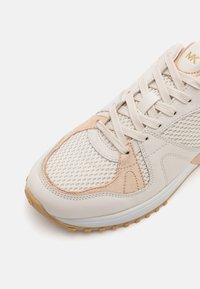 Lichtbeige sneaker met een bovenwerk van mesh, suède accenten en een rubberen zool. Voorzien van een vetersluiting en een vergroot logo op de tong.
