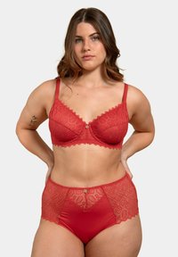 Ensemble de soutien-gorge en dentelle rouge et culottes taille haute avec des motifs floraux, des bords festonnés et un détail décoratif central en forme de bouton.