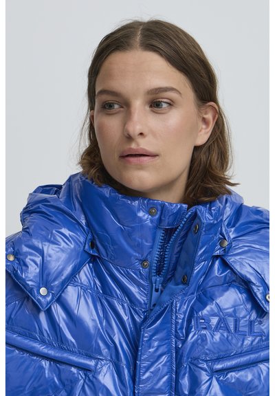 Kék puffertakó fényes, texturált anyagból. Magas gallérral, cipzáras záródással, patentgombokkal és oldalsó zsebekkel rendelkezik. Kék "BALL" logó.