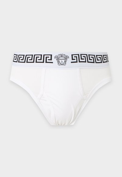 Slip blanc avec une ceinture à motif clé grec noir et logo tête de Méduse au centre, présenté sur un fond uni clair.