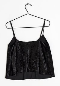 Svart linne i sammet med tunna band. Har en avslappnad passform och slät textur, hängande på en svart vinkrok.